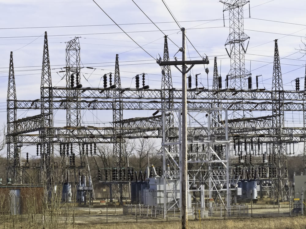 Electrical substation with towers and various steel lattice structures, with telephone pole in foreground, before sunset in spring