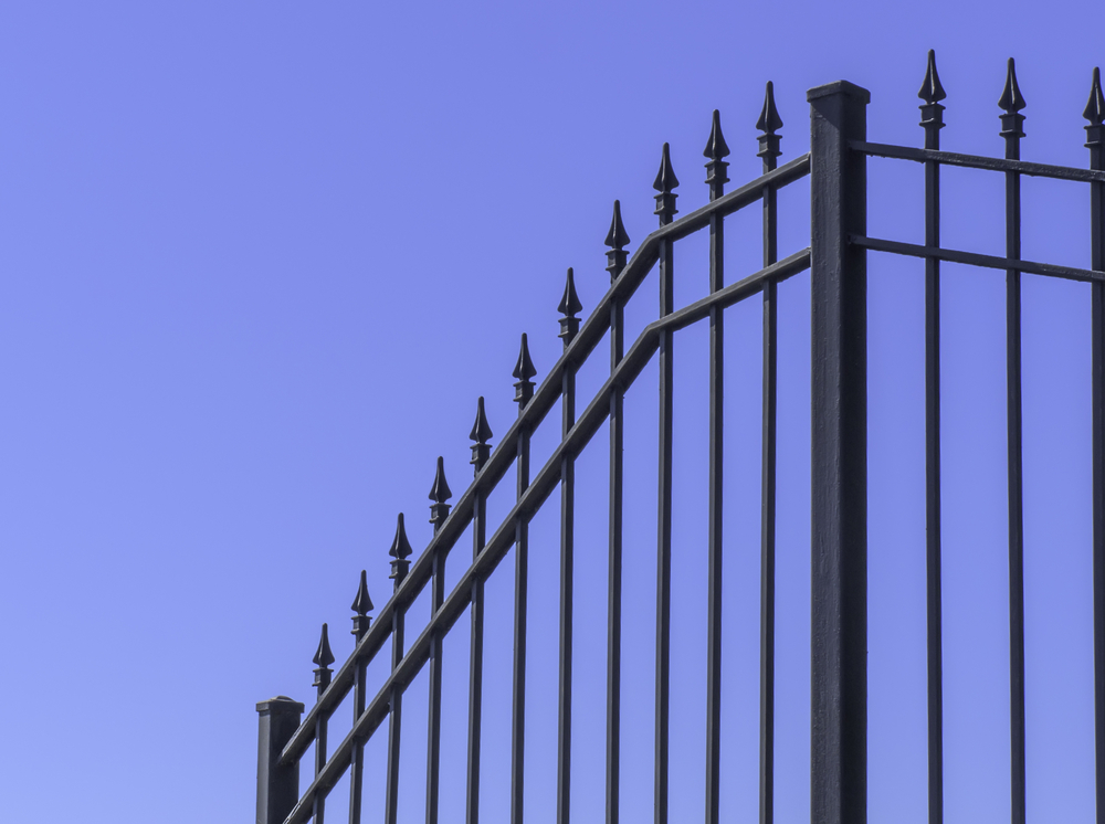 Section of wrought iron fence at top of hill with blue sky for copy space Section of wrought iron fence at top of hill with blue sky for copy space
